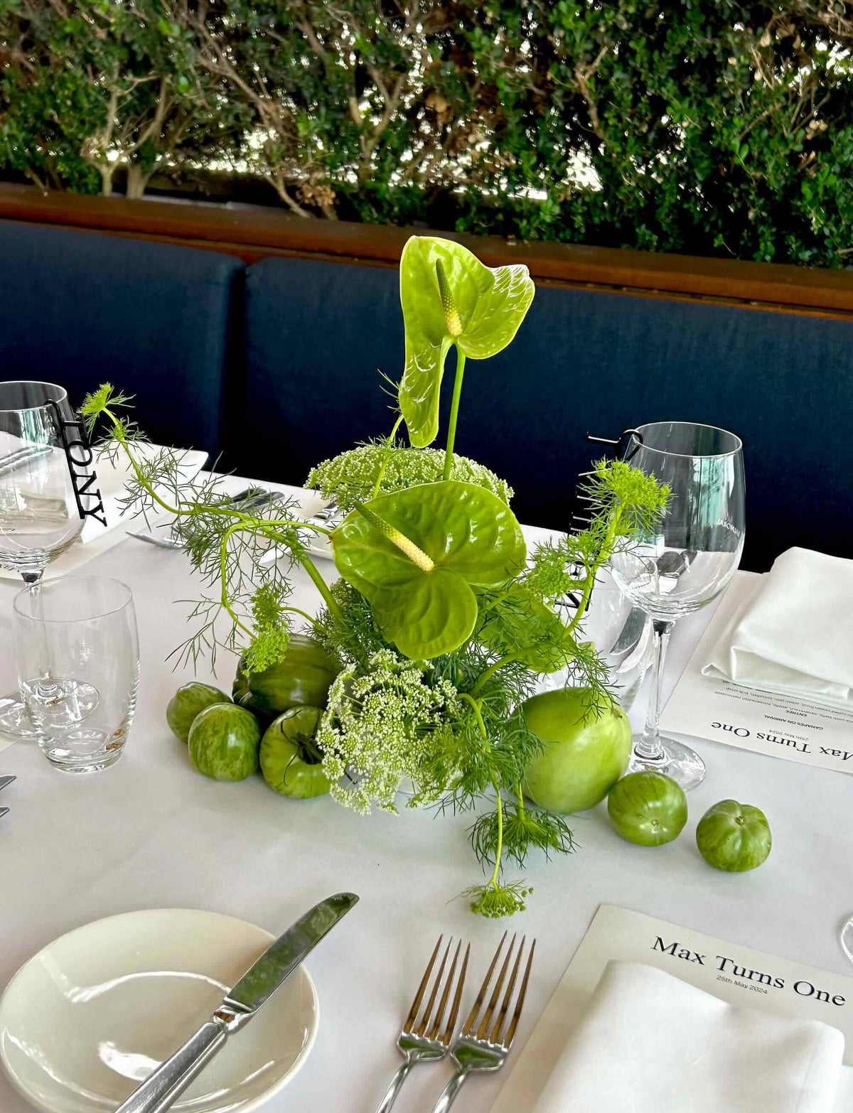 green anthurium event flower arrangement with fruit styling table at restaurant birthday party