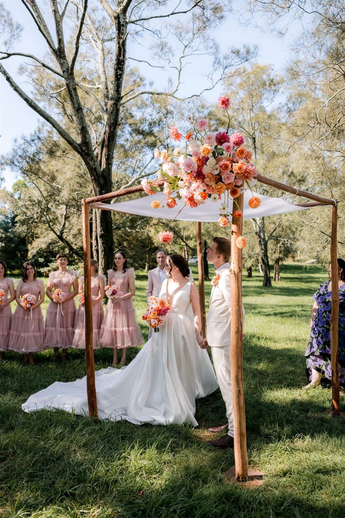 couple standing underneath jewish chuppah in sydney garden decorated with fresh flowers for a wedding