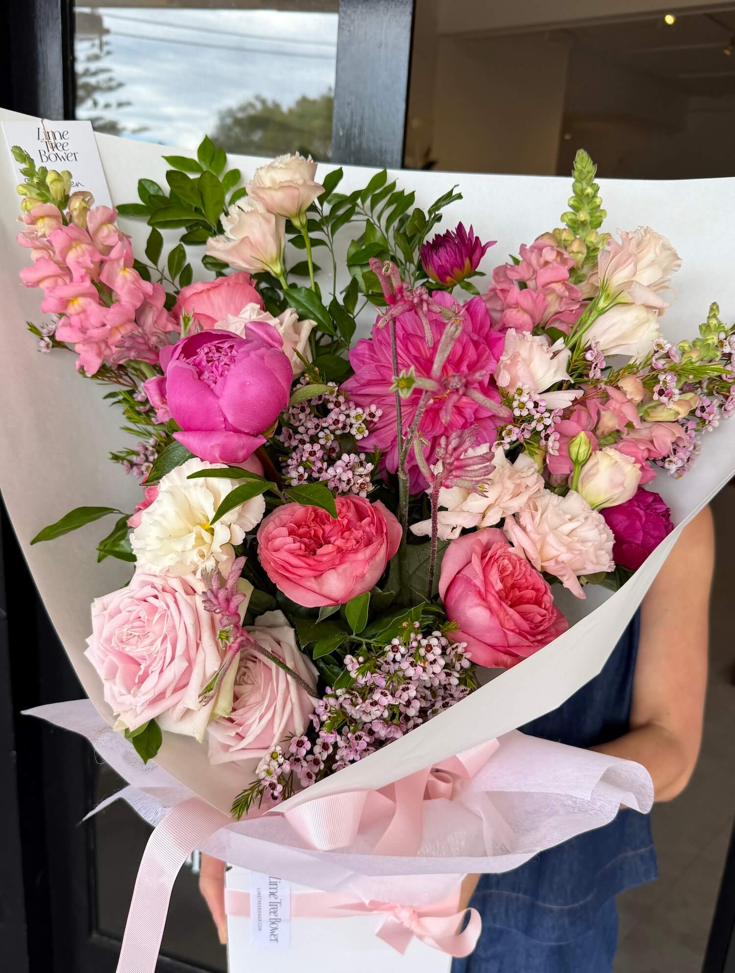 Bouquet of pink and white flowers held by a person with a blurred background