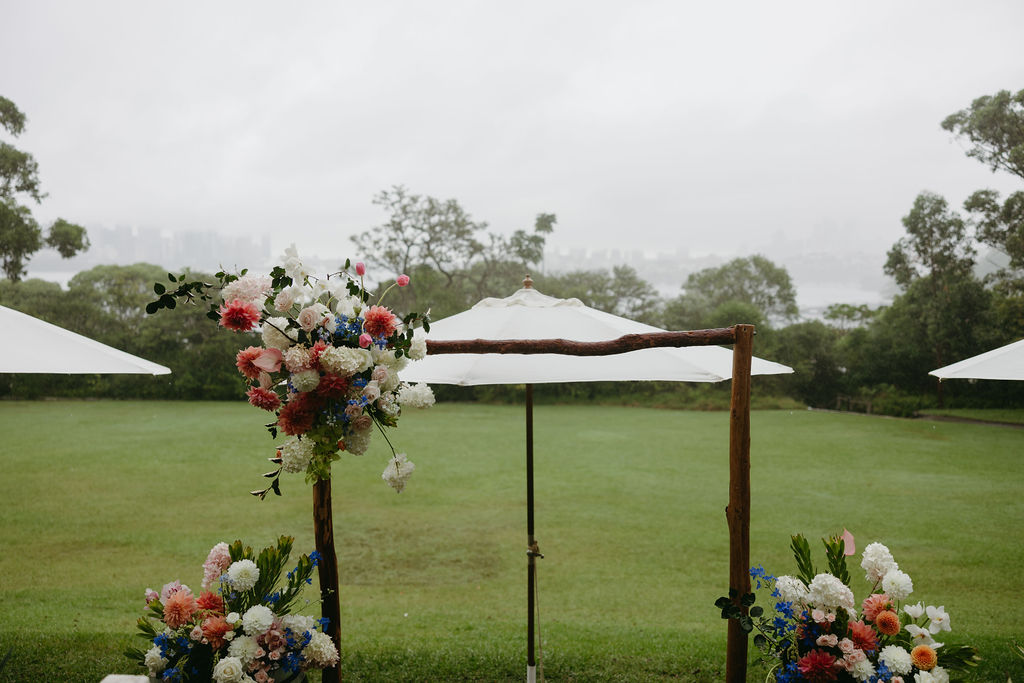 Lawn ceremony at Athol Hall with a floral chuppah, aisle arrangements and white market umbrellas