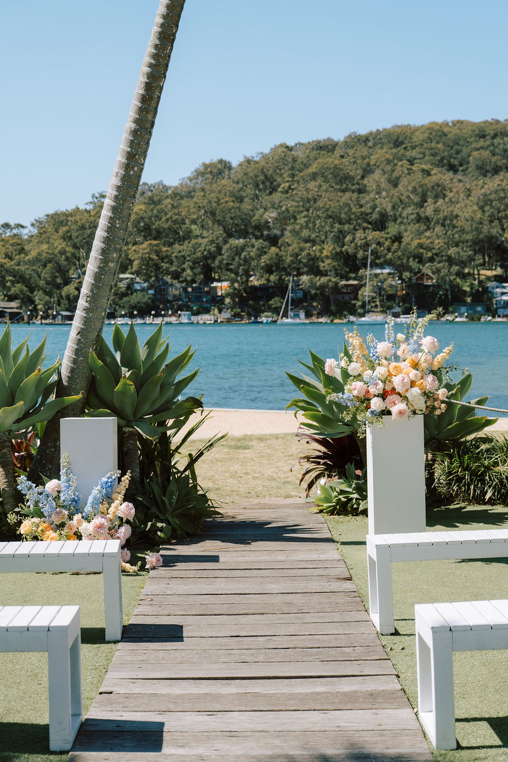 Ceremony on the waterfront lawn at Pasadena, Church Point, with two plinth arrangements and Pittwater behind