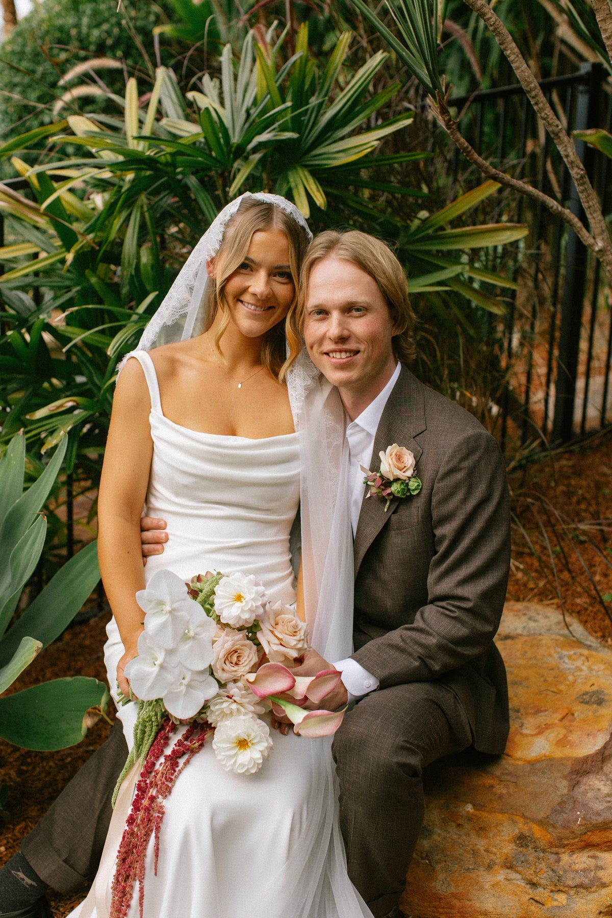 Tayla and Hamish with an autumn-toned bouquet of blush roses, dahlias and trailing amaranthus