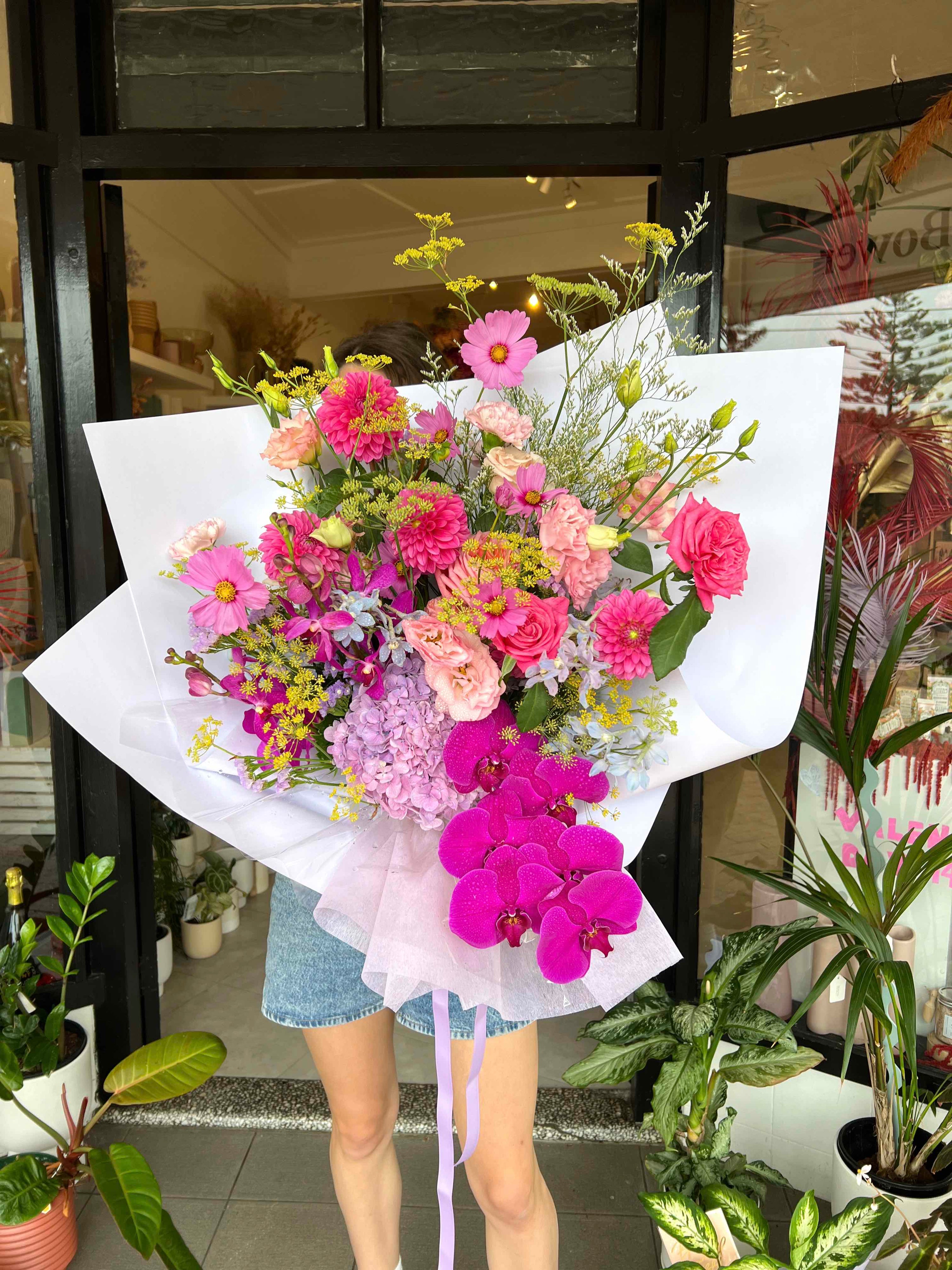 beautiful fresh pink flowers wrapped paper bouquet in front of flower shop 