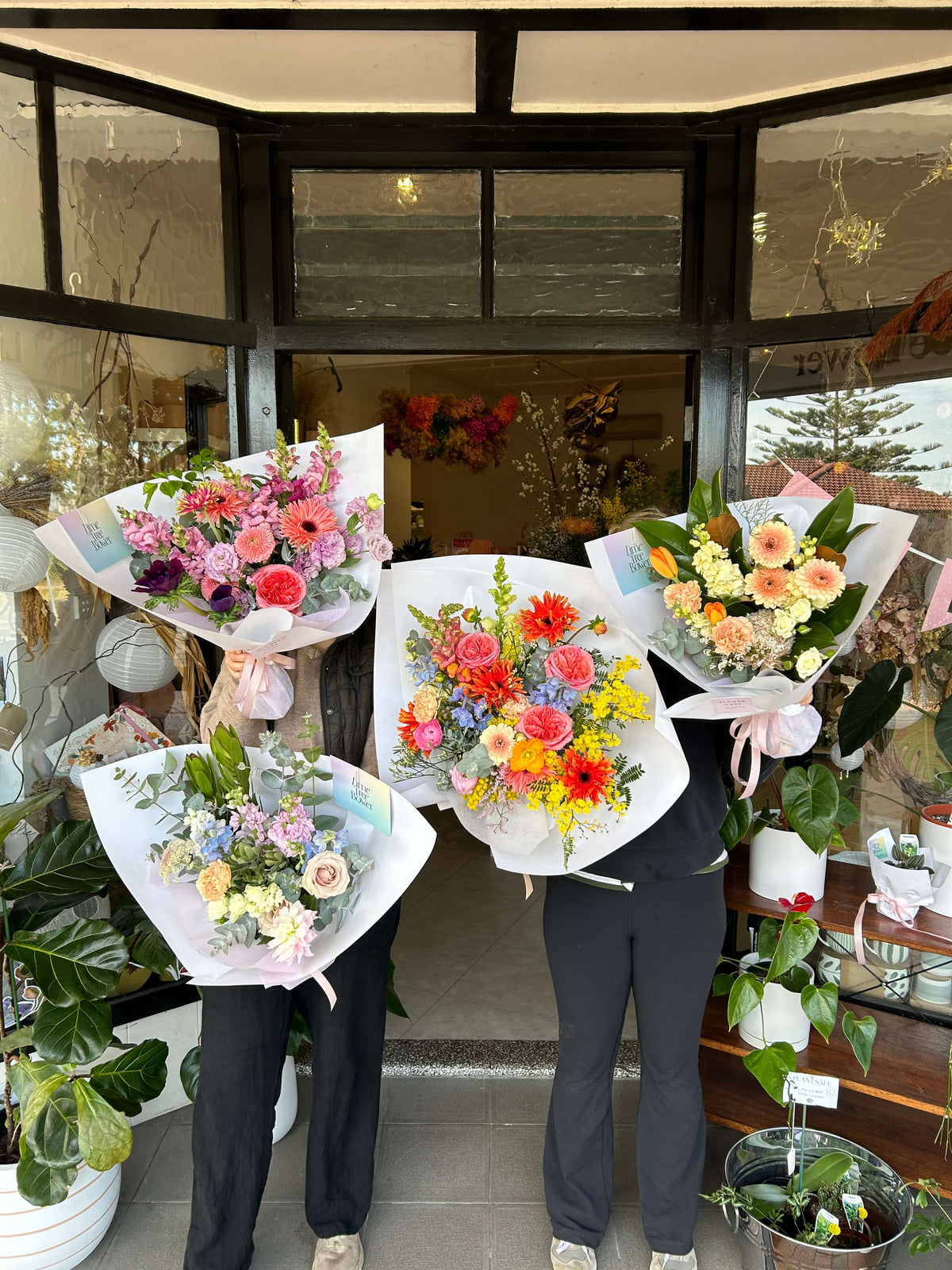 flower bouquets held by florists in front of flower shop sydney
