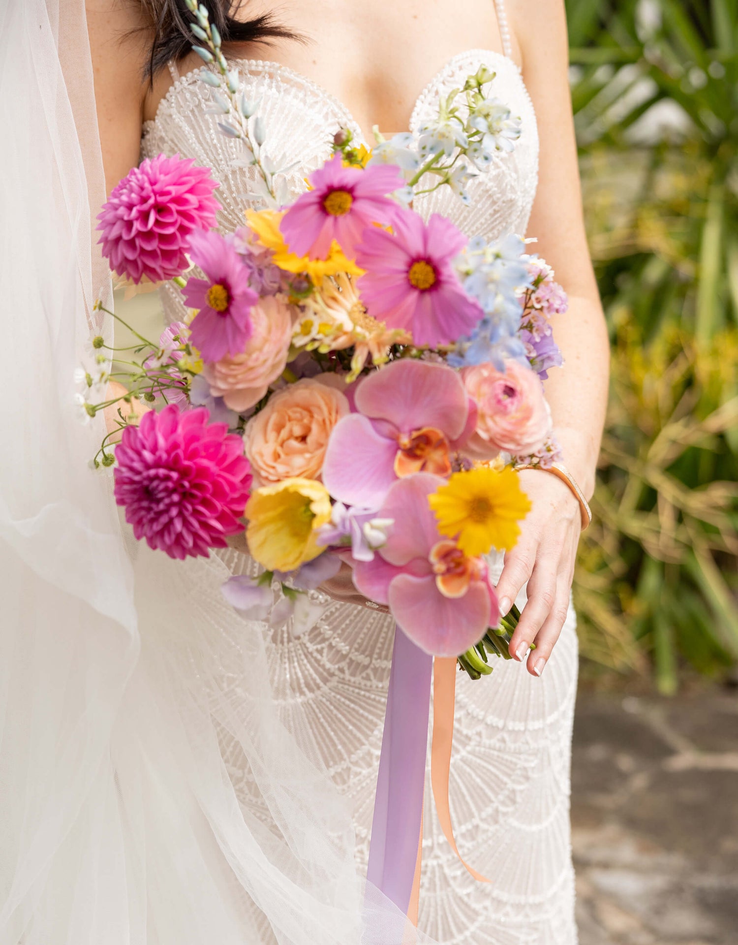 beautiful bridal bouquet pink yellow peach dahlias roses held by bride in wedding dress