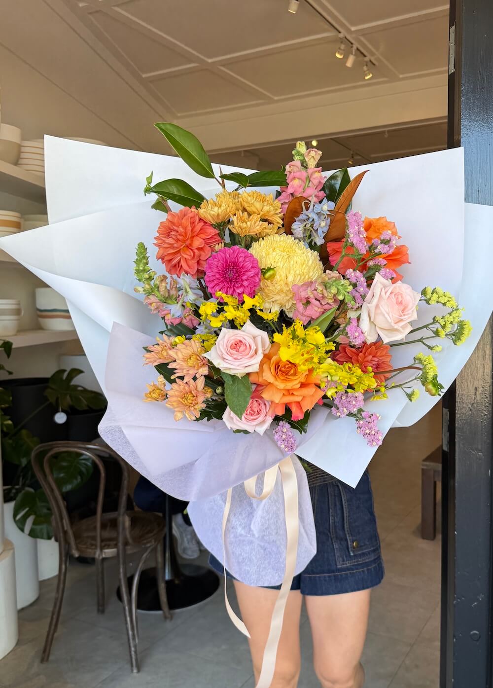 Bouquet of colourful mothers day flowers held by a person featuring dahalias roses magnolia snapdragons