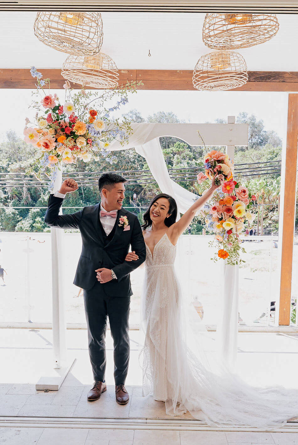 small wedding beach ceremony colourful flower arch couple 